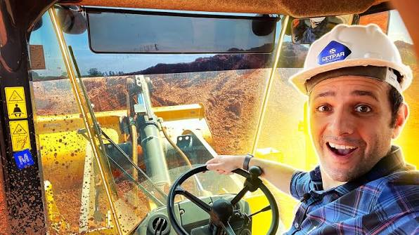 Apresentador dentro da cabine de uma máquina em obra de terraplanagem de um novo bairro